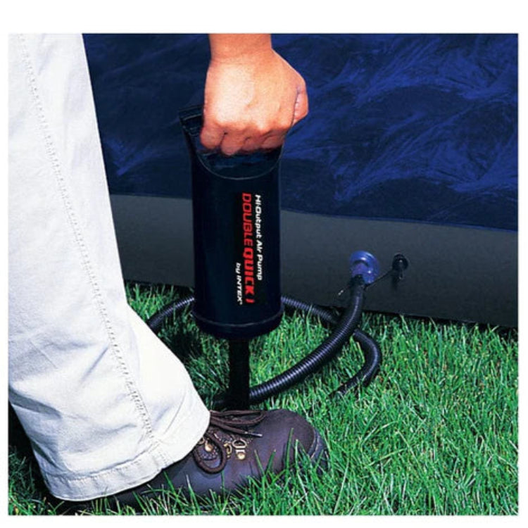 Person inflating an air mattress with a pump labeled 'Highway 61' on a grassy surface.