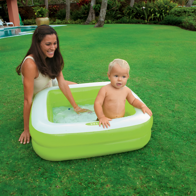 Woman and child playing in a green inflatable pool on grass