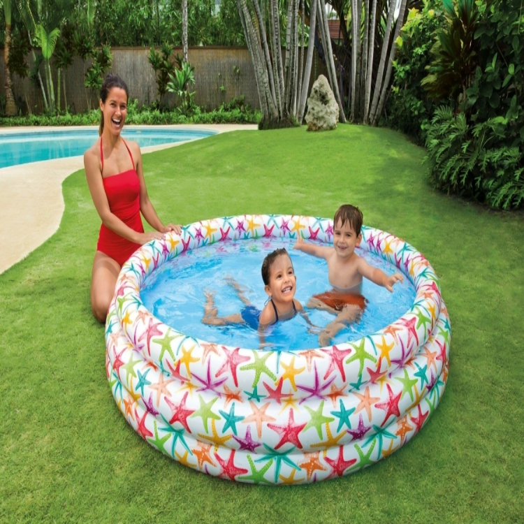 Woman and two children playing in a colorful inflatable pool on grass
