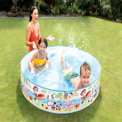 Children playing in a inflatable pool with a woman supervising on a grassy area.